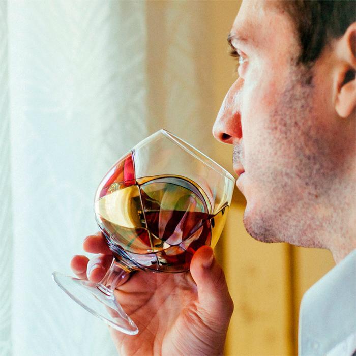 Man drinking from a luxury hand-painted brandy glass inspired by the designs of Antoni Gaudiand Sagrada Familia. Detail colours. Cornet Barcelona  
