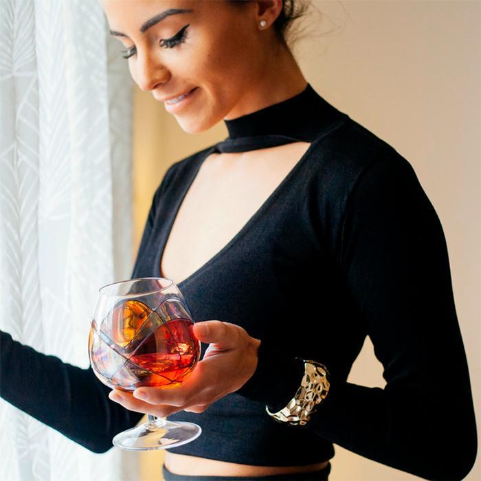 Woman holding a luxury hand-painted full brandy glass inspired by the designs of Antoni Gaudi and Sagrada Familia. Cornet Barcelona 